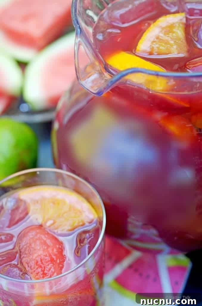 Pitcher of homemade sangria with vodka and glass and tray of watermelon.