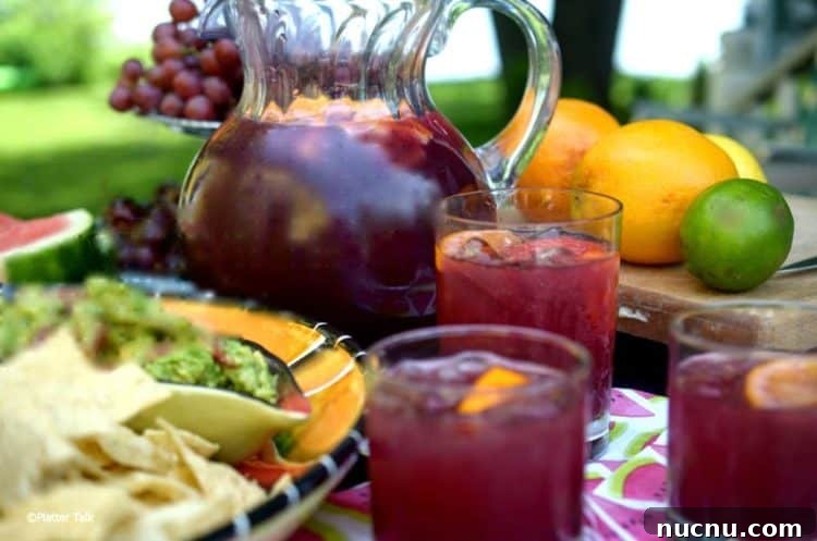 Outdoor table of homemade sangria, oranges, grapes and a bowl of guacamole.