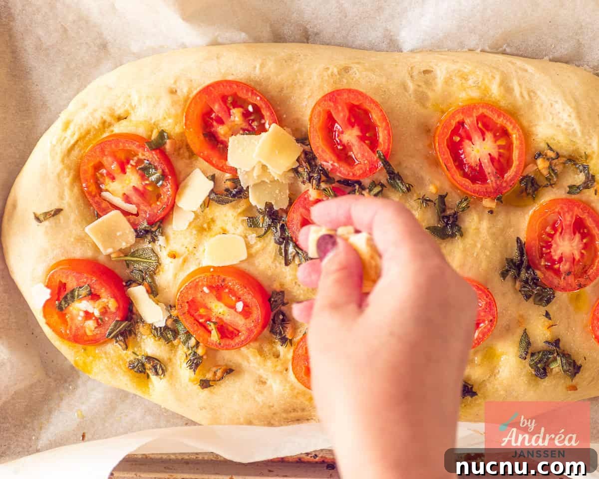 Crispy-Edged Tomato Focaccia with Parmesan and Olive Oil 7 Halfway through the baking time, Parmesan cheese is spread over the top of the bread.