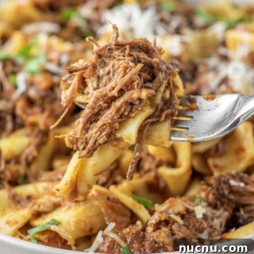 spoon lifting out pasta with meat from bowl