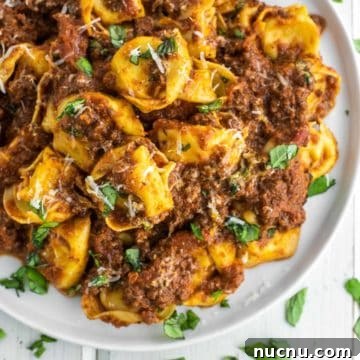 overhead shot of bolognese with tortellini on white plate