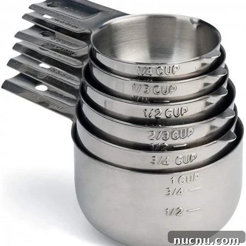 A nested stack of stainless steel measuring cups, each labeled with different measurements including 1/4 cup, 1/3 cup, 1/2 cup, 2/3 cup, 3/4 cup, and 1 cup.