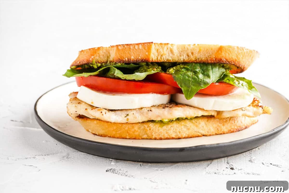 Caprese Chicken Sandwich with Fresh Mozzarella & Basil 12 side view of sandwich with chicken breast mozzarella tomato and basil