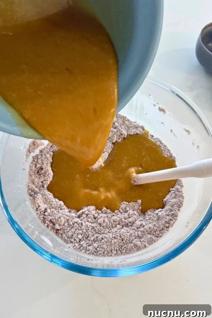Pouring wet ingredients into dry ingredients to make the dough for sourdough Halloween cookies.