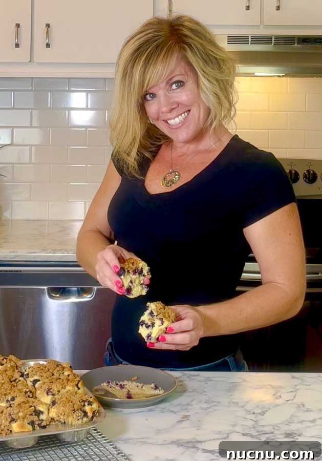 Blueberry Sour Cream Muffins with Crunchy Streusel Topping 3 Jennifer holdig a blueberry muffin
