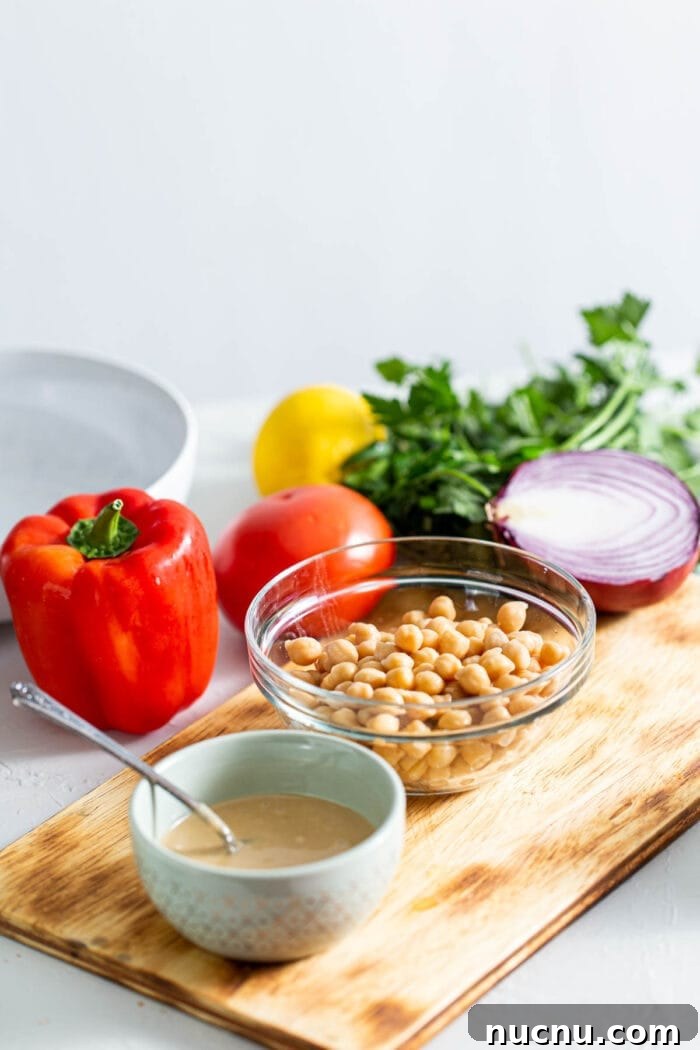 Essential Vegan Pantry Staples for Everyday Cooking 8 Chickpeas, tahini, bell pepper, onion, parsley and red onion on a cutting board.