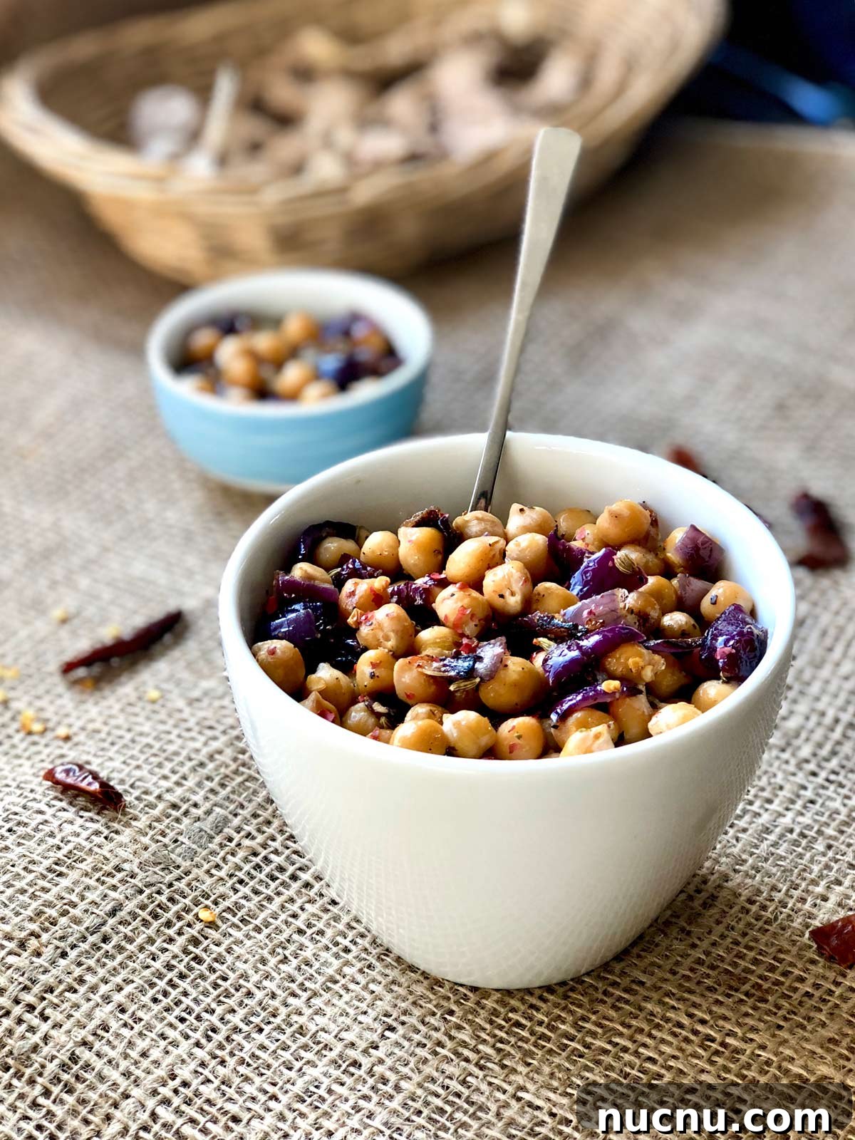Garlic Lemon Sautéed Chickpeas with Crispy Edges 2 Sauteed chickpeas in a white serving bowl with a teaspoon tucked in.