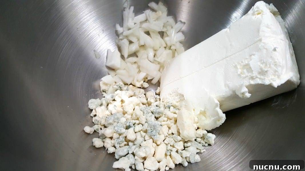 4-Ingredient Beer Cheese Dip Recipe for Game Day 3 onions, blue cheese and cream cheese in a bowl.