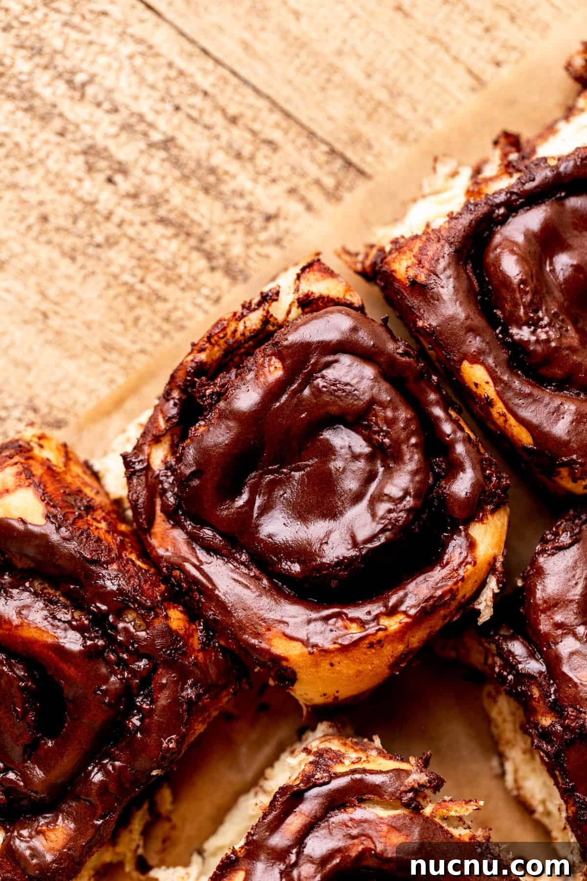 Decadent Chocolate Cinnamon Rolls with Gooey Chocolate Swirl 3 Chocolate cinnamon rolls on parchment paper.