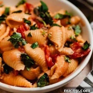Creamy pasta with tomatoes and spinach topped with chopped fresh basil.