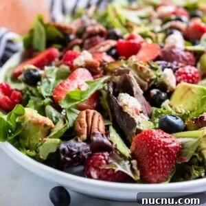 Berries and pecans over green salad.