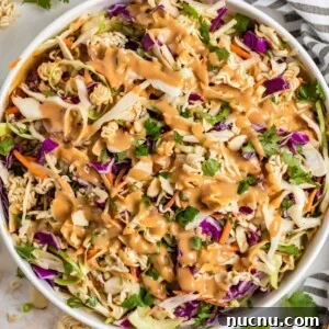 Ramen cabbage salad with peanut dressing over top in white bowl.
