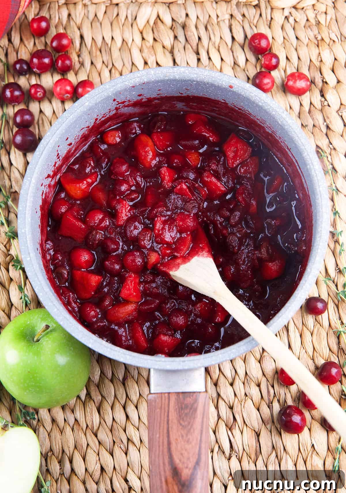 Tangy Cranberry Chutney Recipe for Holiday Roasts and Cheese 3 Cranberry chutney is being cooked in a pot and stirred with a spoon.