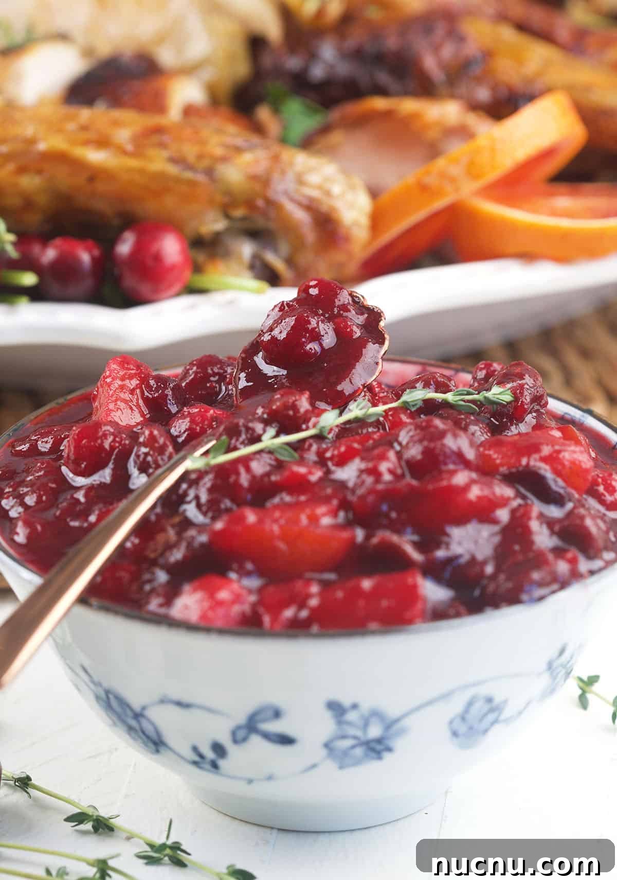 Tangy Cranberry Chutney Recipe for Holiday Roasts and Cheese 5 A spoon holding cranberry chutney is placed on a bowl.