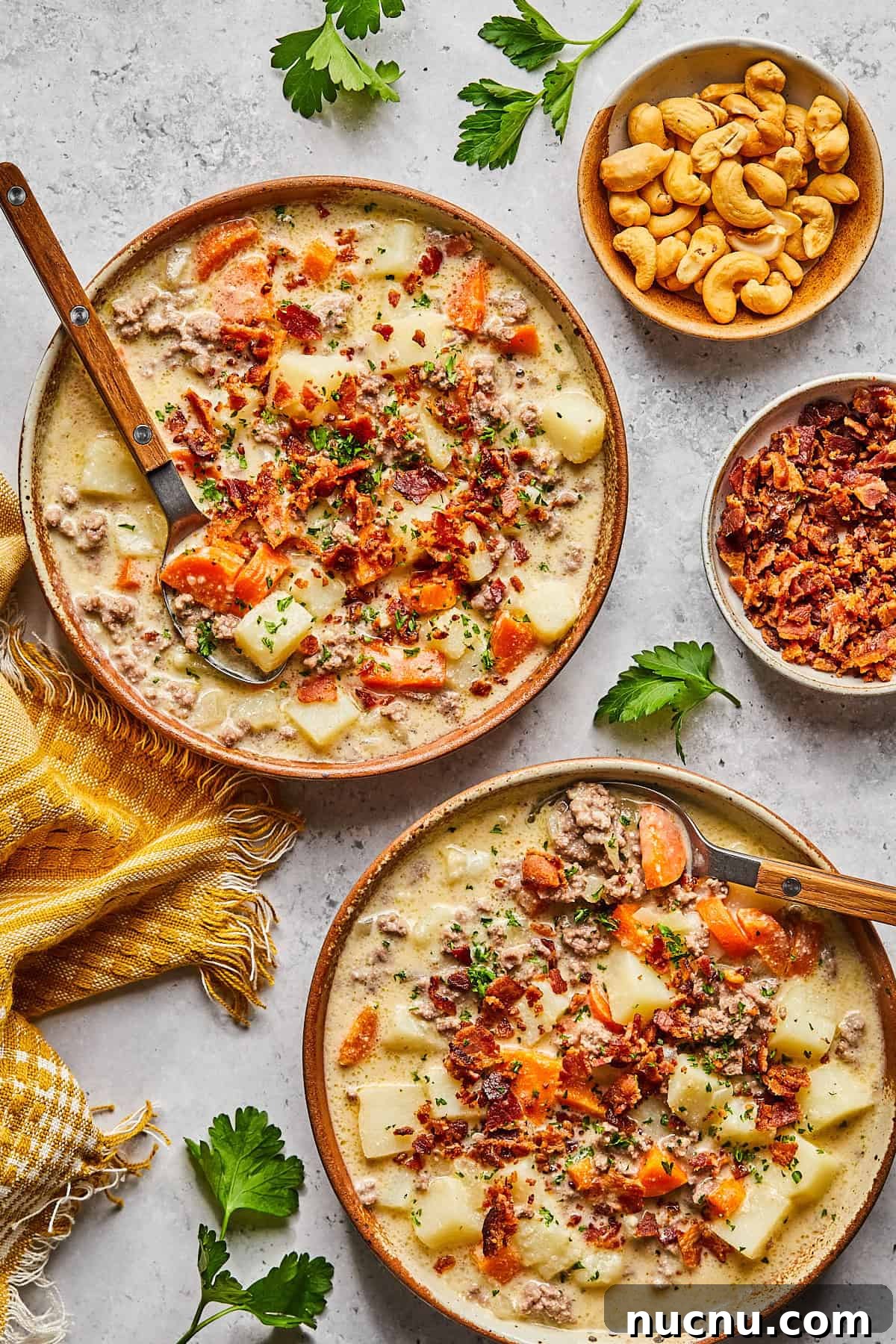 2 bowls of cheeseburger soup surrounded by toppings