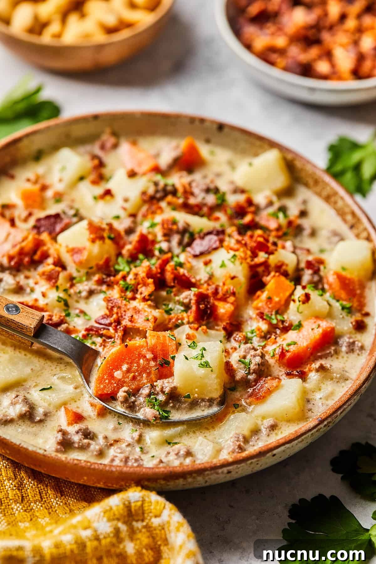 a side view of cheeseburger soup topped with bacon and parsley
