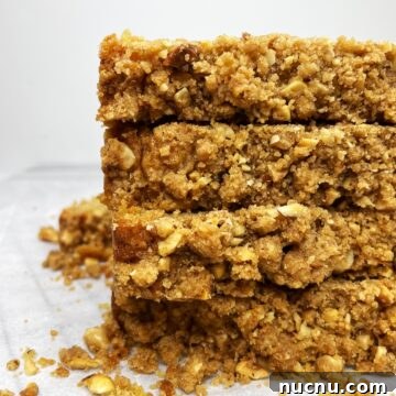 Stacked slices of apple crumble bread on parchment.