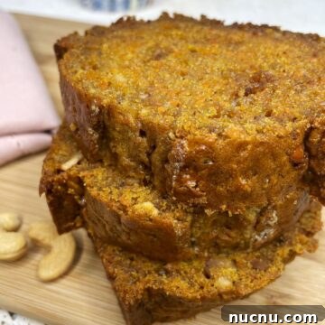 Three slices of carrot loaf on a wooden board.