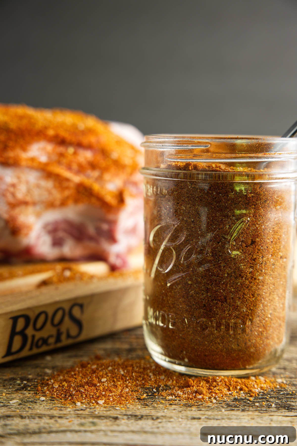 Savory Pork Butt Dry Rub Recipe for Juicy Barbecue 2 jar of pork butt rub with a seasoned pork butt in the background