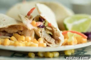 fish taco with a bit taken out on a plate with corn and lime wedge