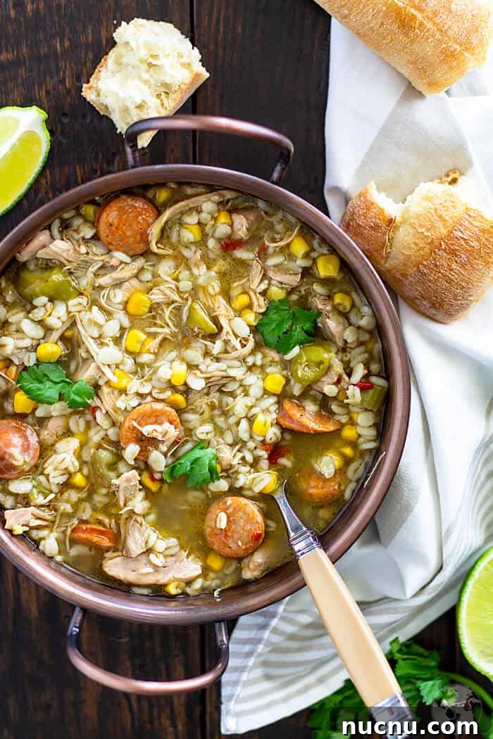 Cajun Chicken and Barley Gumbo Recipe for Comforting Flavor 2 Gumbo soup in a copper bowl with a spoon and bread pieces.