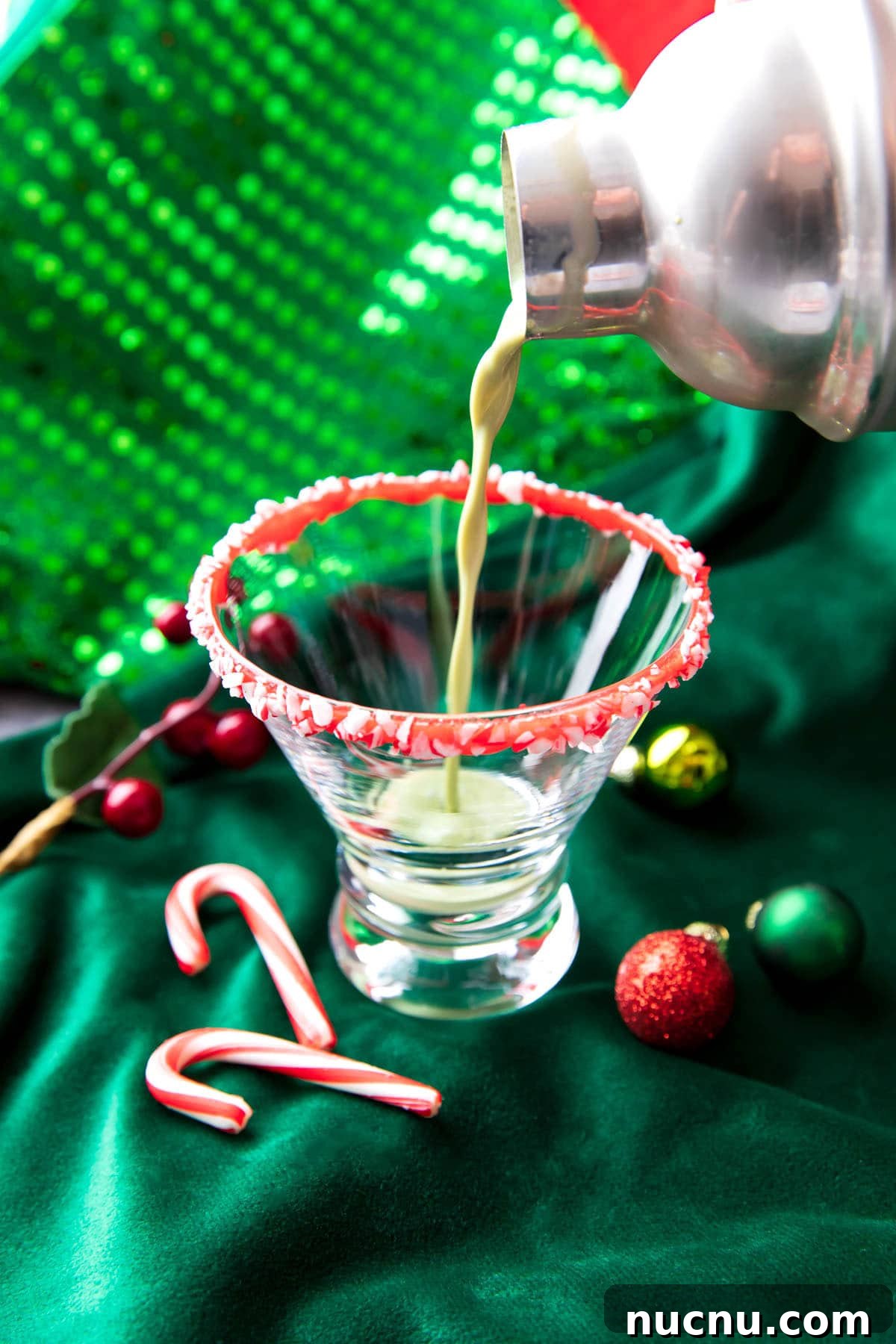 Peppermint Martini Recipe: How to Make a Refreshing Holiday Cocktail 3 Someone pouring a peppermint martini mixture into a martini glass.