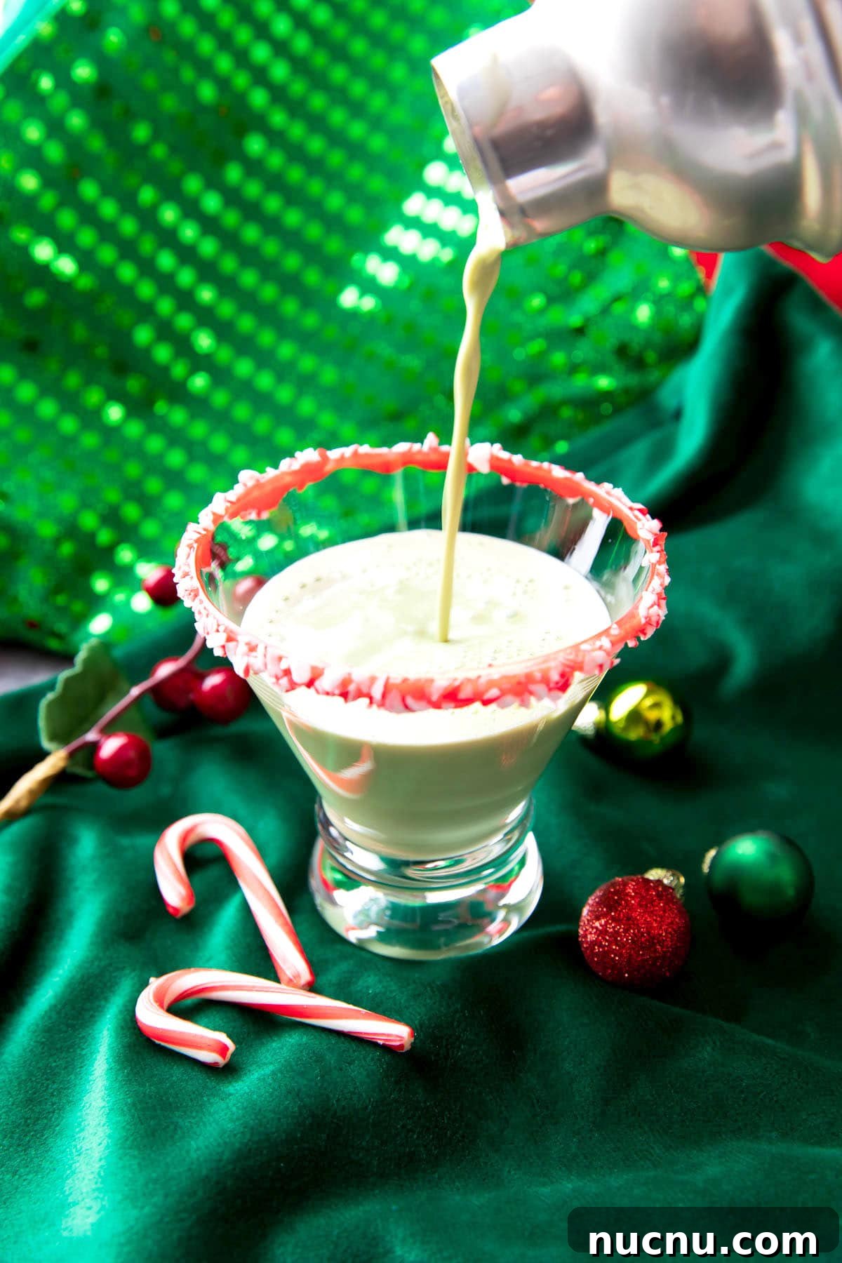 Peppermint Martini Recipe: How to Make a Refreshing Holiday Cocktail 4 Someone straining peppermint martini mixture into a rimmed cocktail glass.