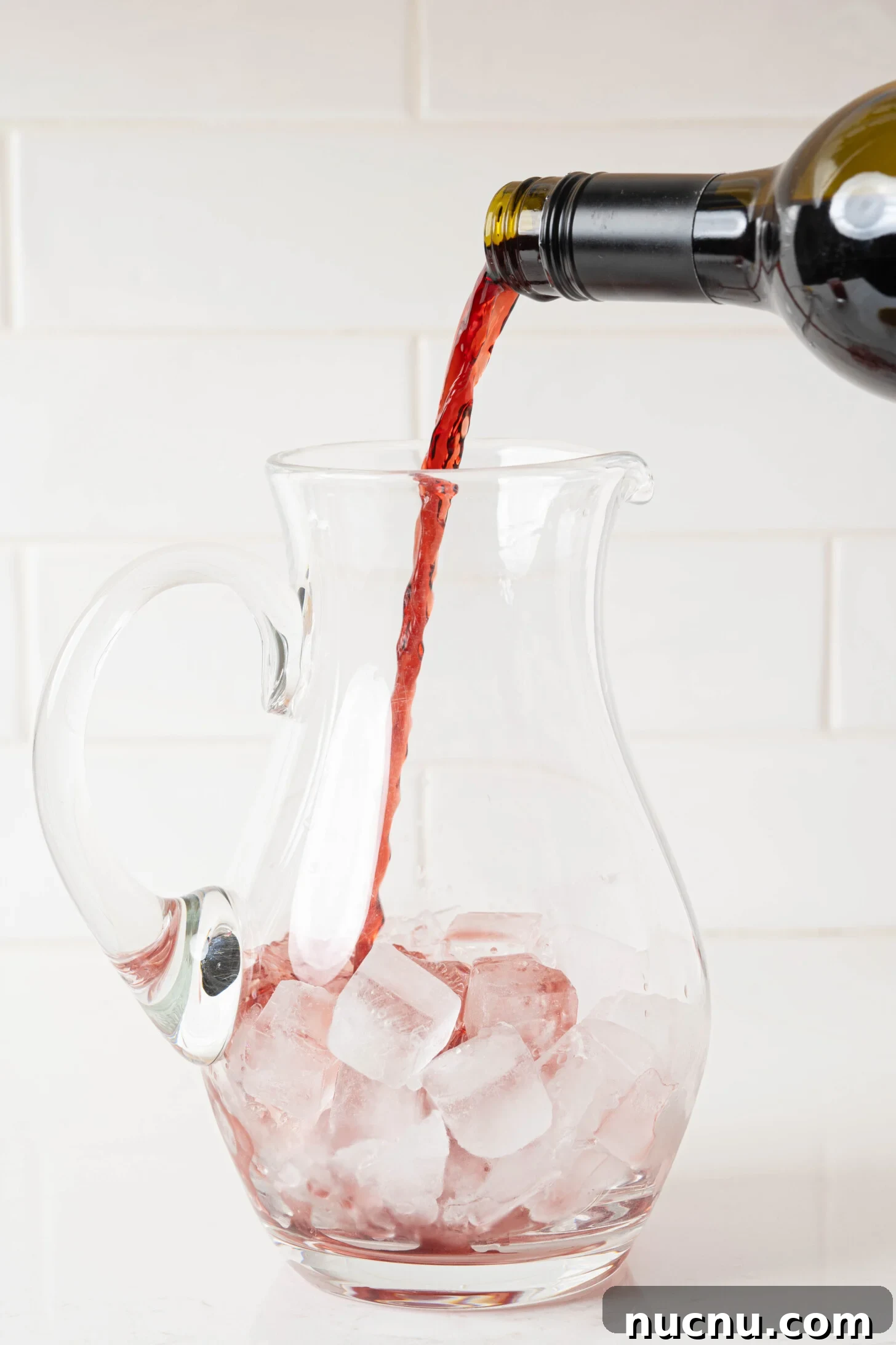 Wine pouring into a pitcher over ice.