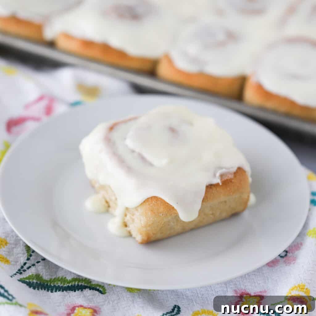 Cinnamon Roll Recipes: Classic, Gooey, and Irresistible Options 3 A cinnamon roll on a white plate topped with cinnamon roll frosting.