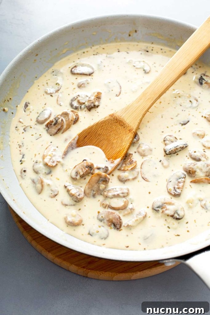 mushrooms with heavy cream on a skillet with a wooden spoon