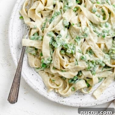 completed Dairy Free Alfredo Sauce with Kale and Peas plated on a white plate against a white surface