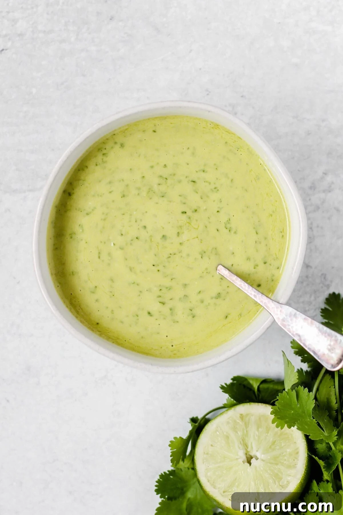 small bowl filled with cilantro dressing with a spoon dipped into bowl.
