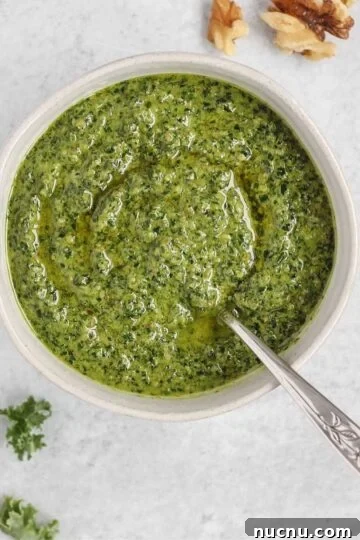 Pesto in a small bowl with a spoon in the pesto.