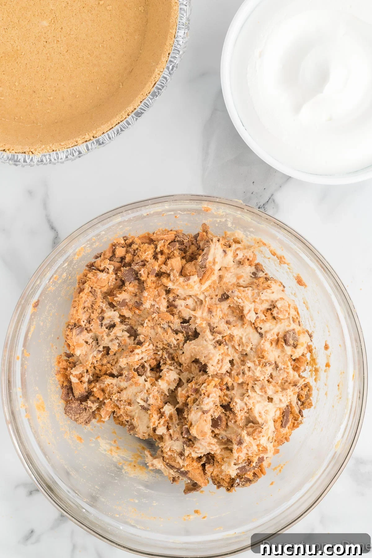 Decadent Butterfinger Pie Recipe — How to Make It at Home 7 Bowl of crushed candy and peanut butter mixture being combined.