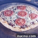 Smoky Brisket Pizza: How to Make Tender BBQ Brisket Pizza 2 Brisket pizza topped with tomato slices on a pizza stone - grilling