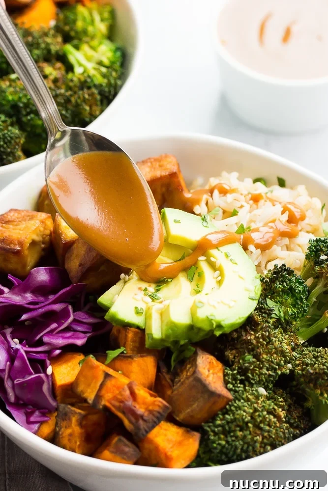 Vibrant Buddha Bowl Recipe: Colorful, Nourishing Lunch Idea 4 buddha bowl with rice, vegetables and tofu with vegan peanut sauce drizzling on top with a spoon.