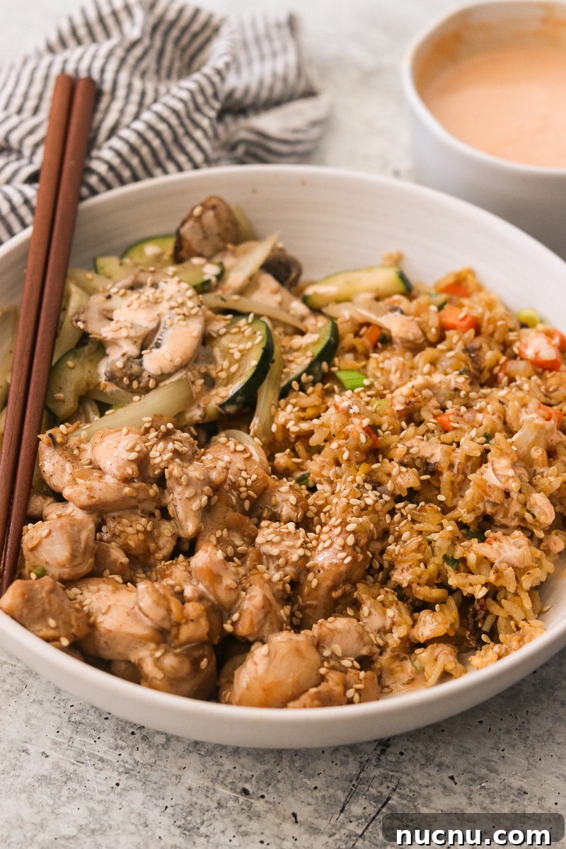 Hibachi Chicken Bowl Recipe — Japanese Steakhouse Copycat 11 Close-up of hibachi chicken bowls garnished with sesame seeds with chopsticks lying in the bowl.