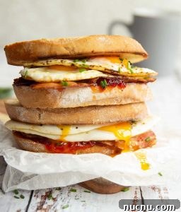 Fried Egg Sandwich two sandwiches stacked on each other with yolk dripping down and mug blurred in background
