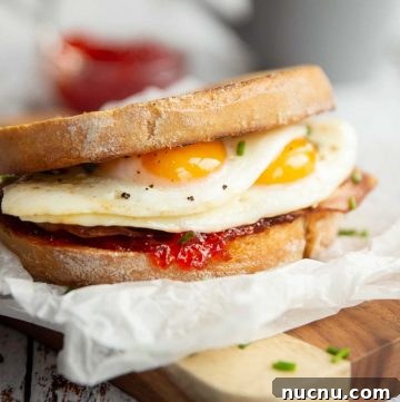 sandwich on wooden chopping board with chilli jam and grey mug blurred in background