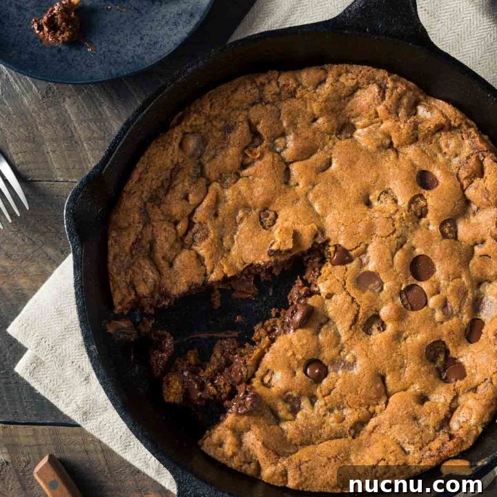 a skillet cookie with one piece removed and placed on a black plate next to the pan