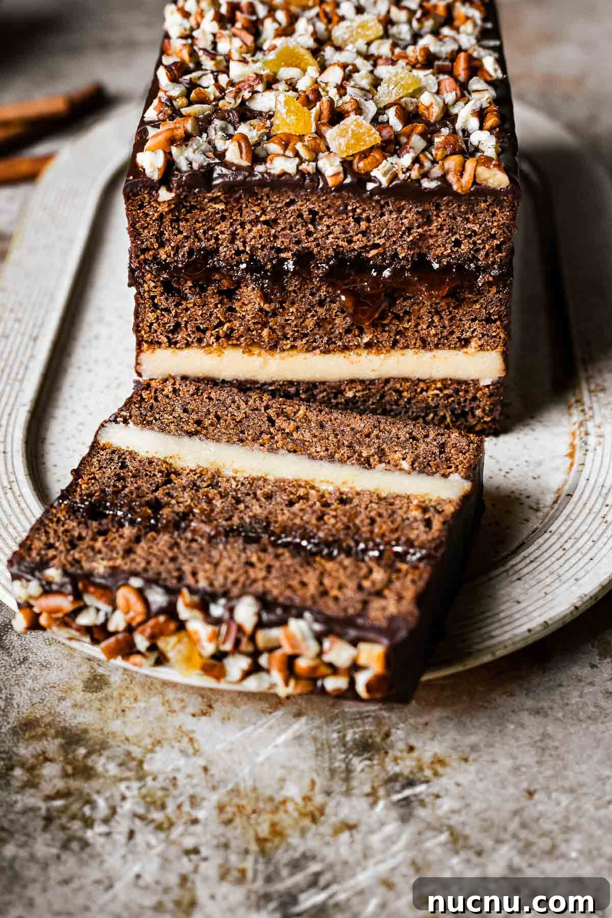 An angled view of a chocolate glazed gingerbread cake revealing the layers.