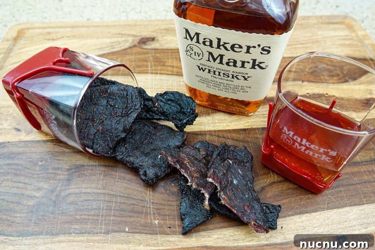 Kentucky Bourbon–Glazed Beef Jerky Recipe 11 beef jerky on cutting board with bourbon bottle