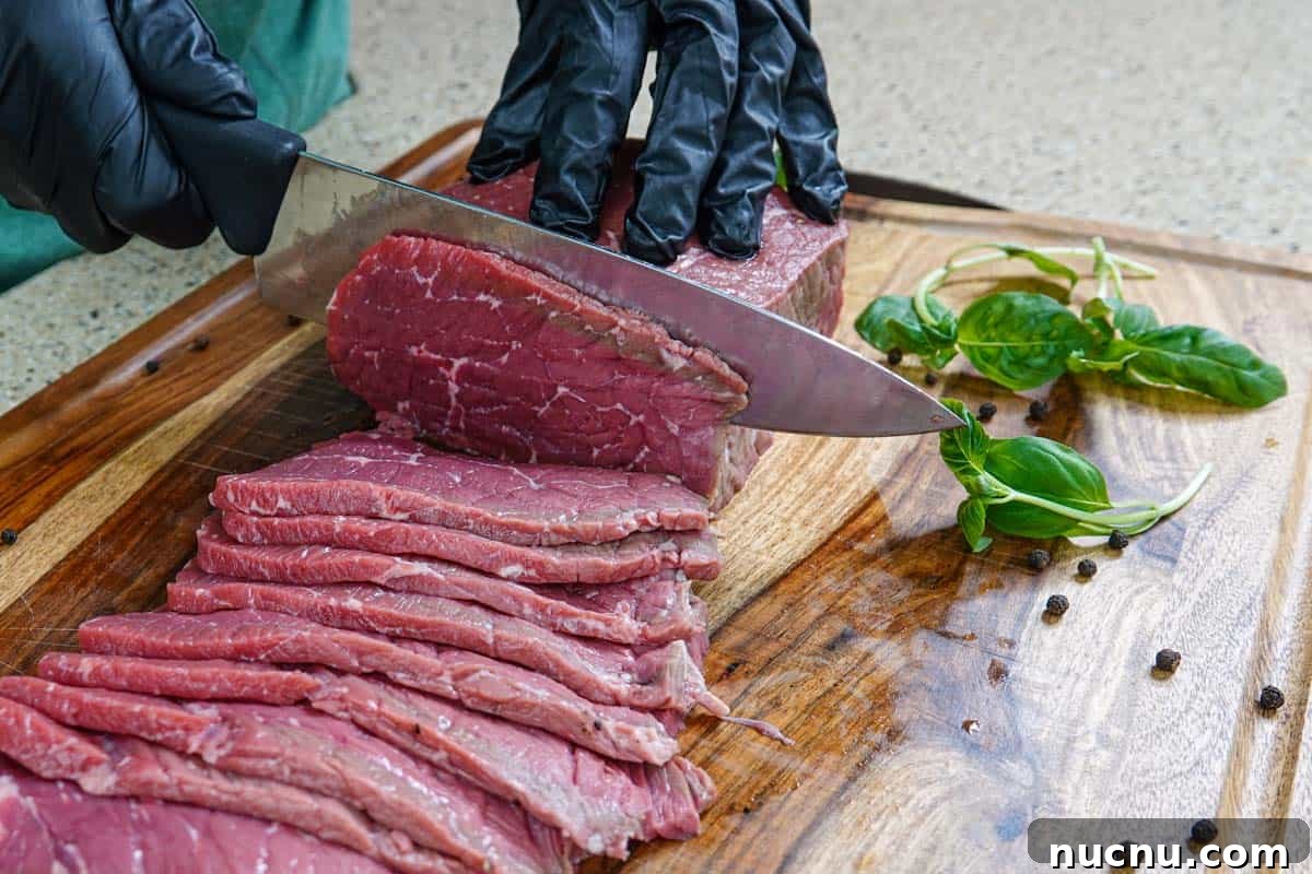 Kentucky Bourbon–Glazed Beef Jerky Recipe 5 Slicing meat for beef jerky on cutting board with knife
