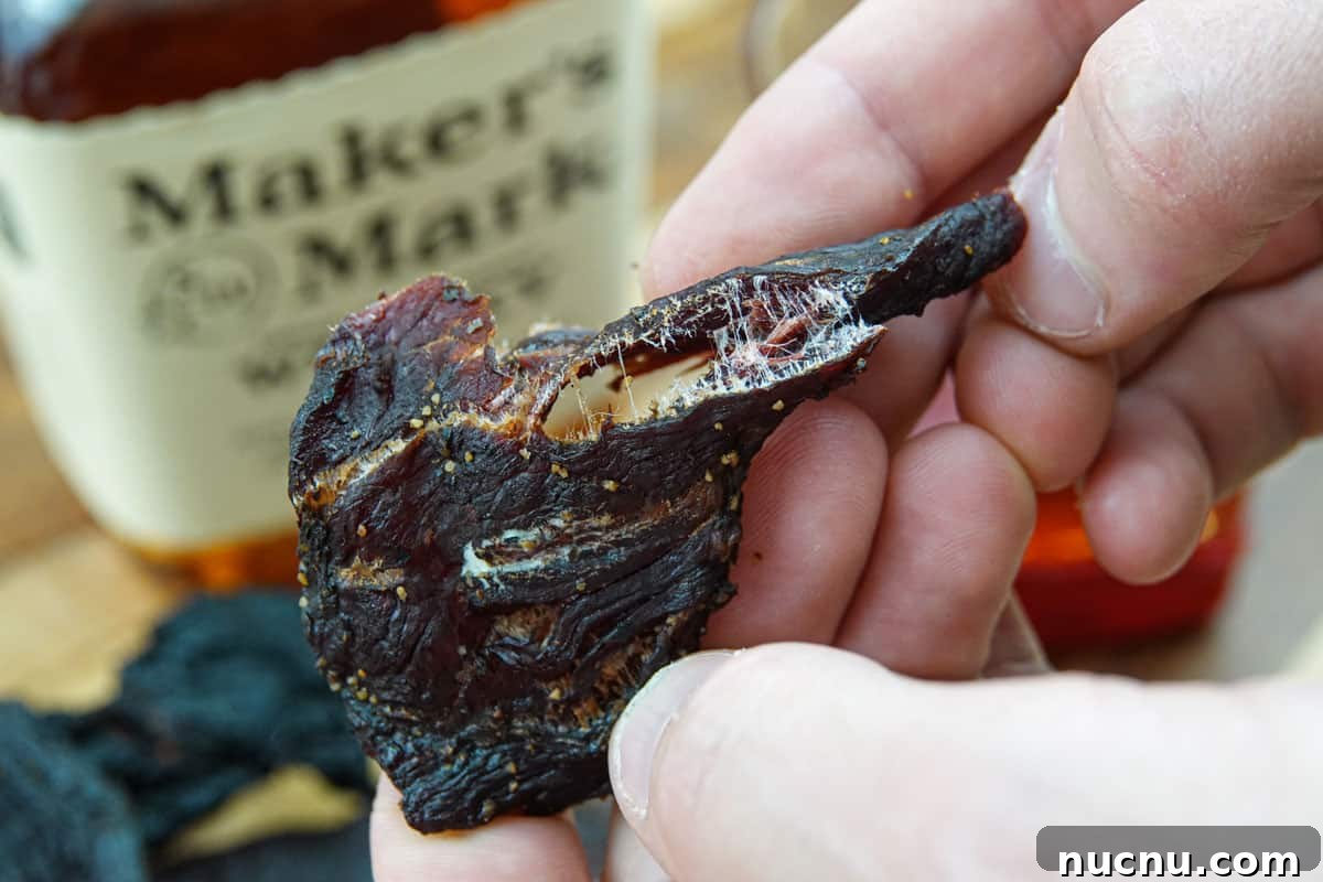 Kentucky Bourbon–Glazed Beef Jerky Recipe 10 Bending a piece of beef jerky in half to see if it's finished drying