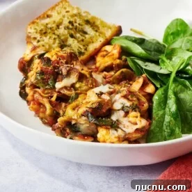 Ultimate Baked Pasta Recipes for Crowd-Pleasing Dinners 14 Baked Tortellini on a plate with spinach and bread.