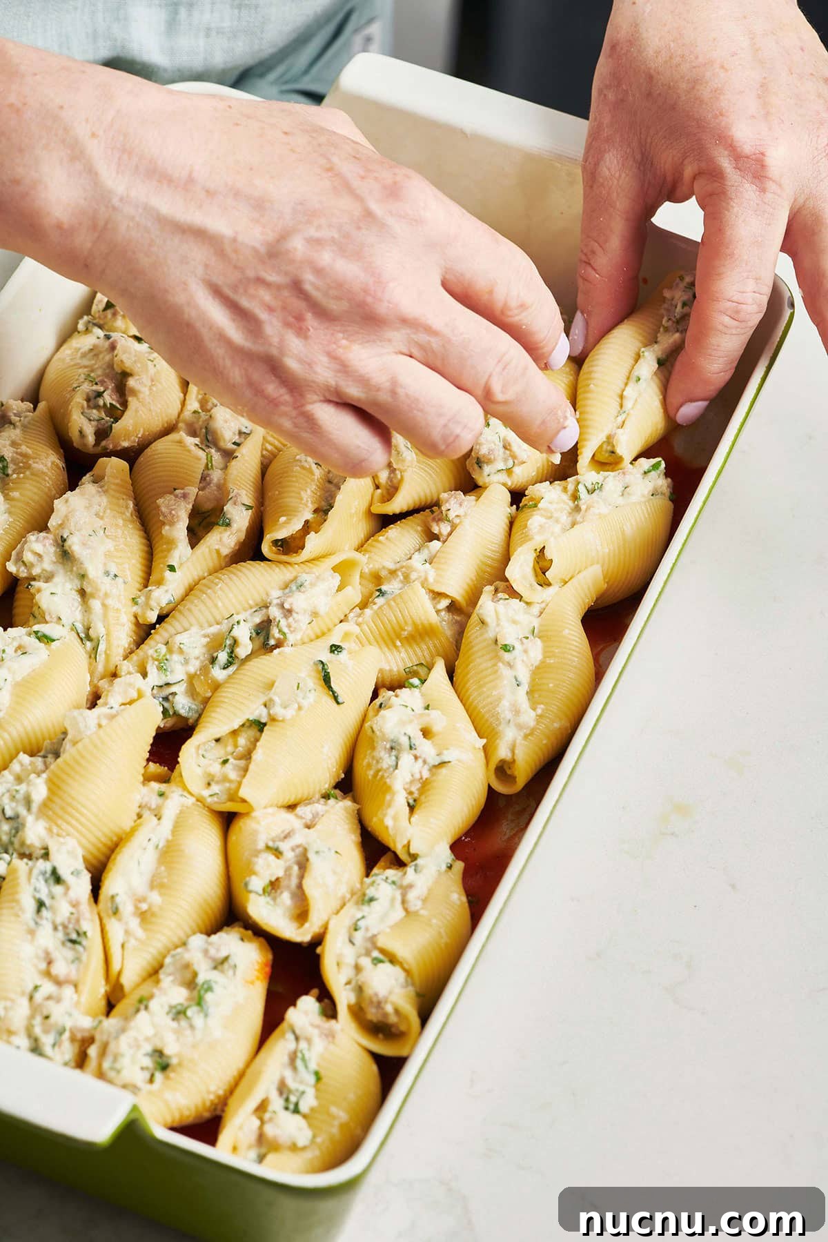 Ultimate Baked Pasta Recipes for Crowd-Pleasing Dinners 4 Woman arranged stuffed pasta shells in a baking dish.