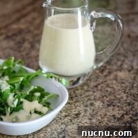 a small pitcher of sour cream dressing with a salad on the side