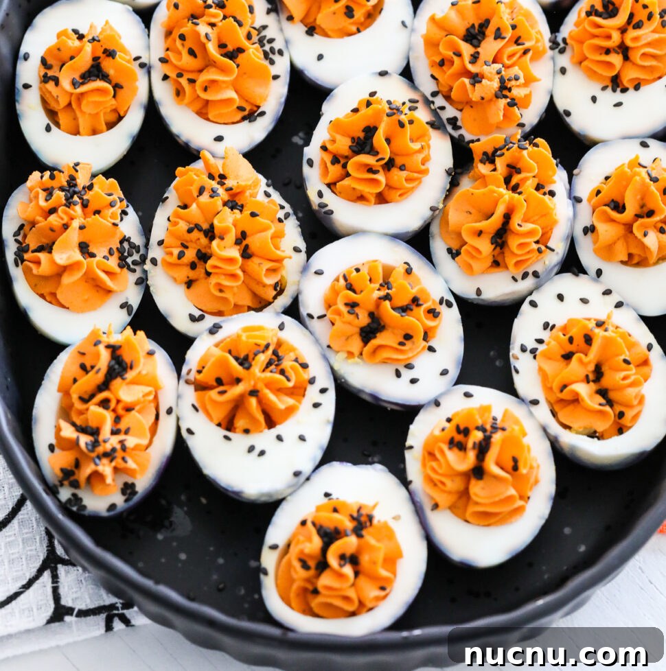 A black platter filled with Halloween deviled eggs sprinkled with black sesame seeds.