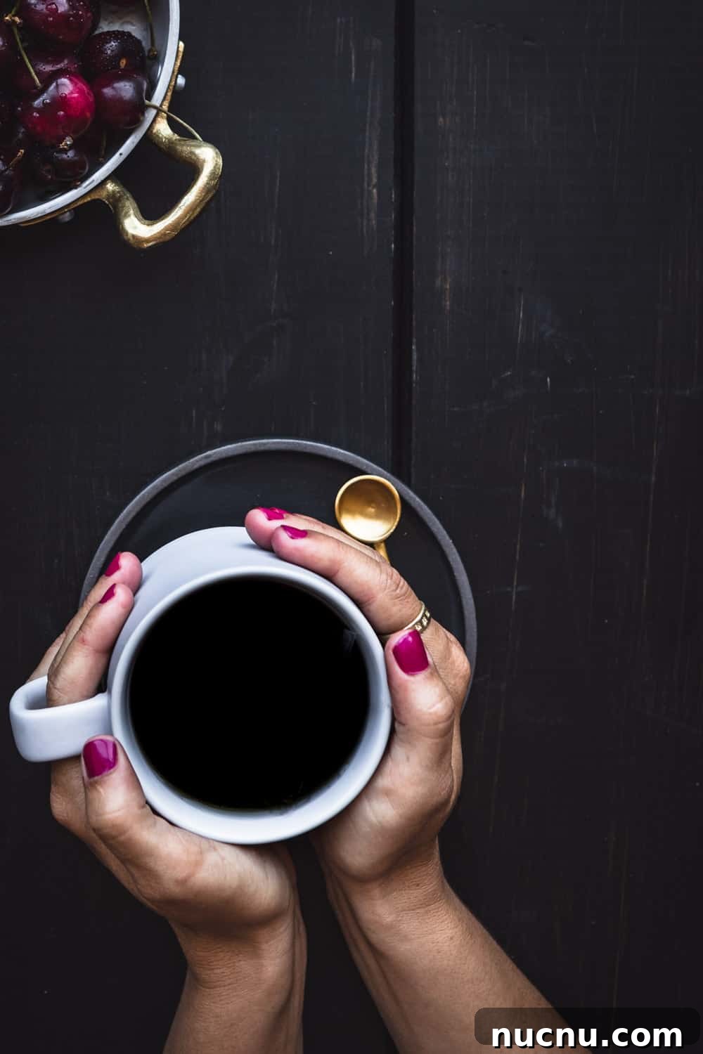 Top San Francisco Coffee Shops for Digital Nomads — 2026 Guide 4 My pink nails holding a cup of black coffee, with a bowl of cherries in the corner.