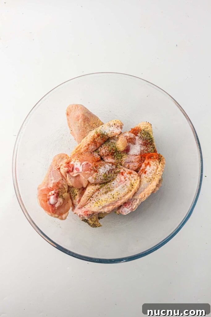 Crispy Air Fryer Chicken Wings — Extra Crunch in 25 Minutes 4 Chicken wings in a bowl with seasonings.